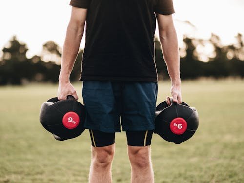 Person Holding Black Dumbbells