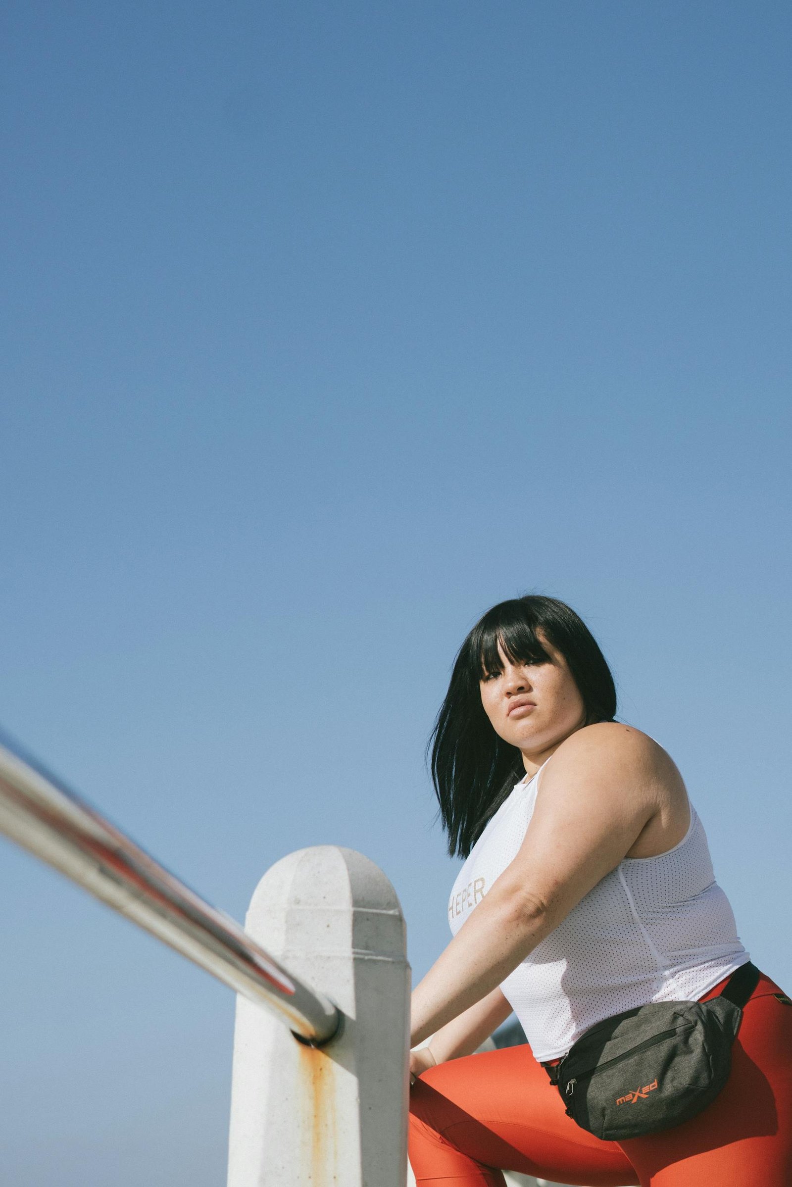 Woman in White Tank Top Leaning on Metal Railing