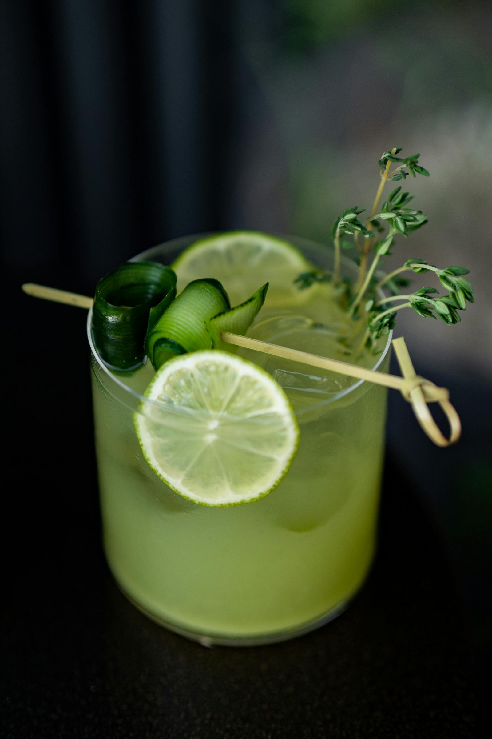 A green drink with cucumber and lime garnish