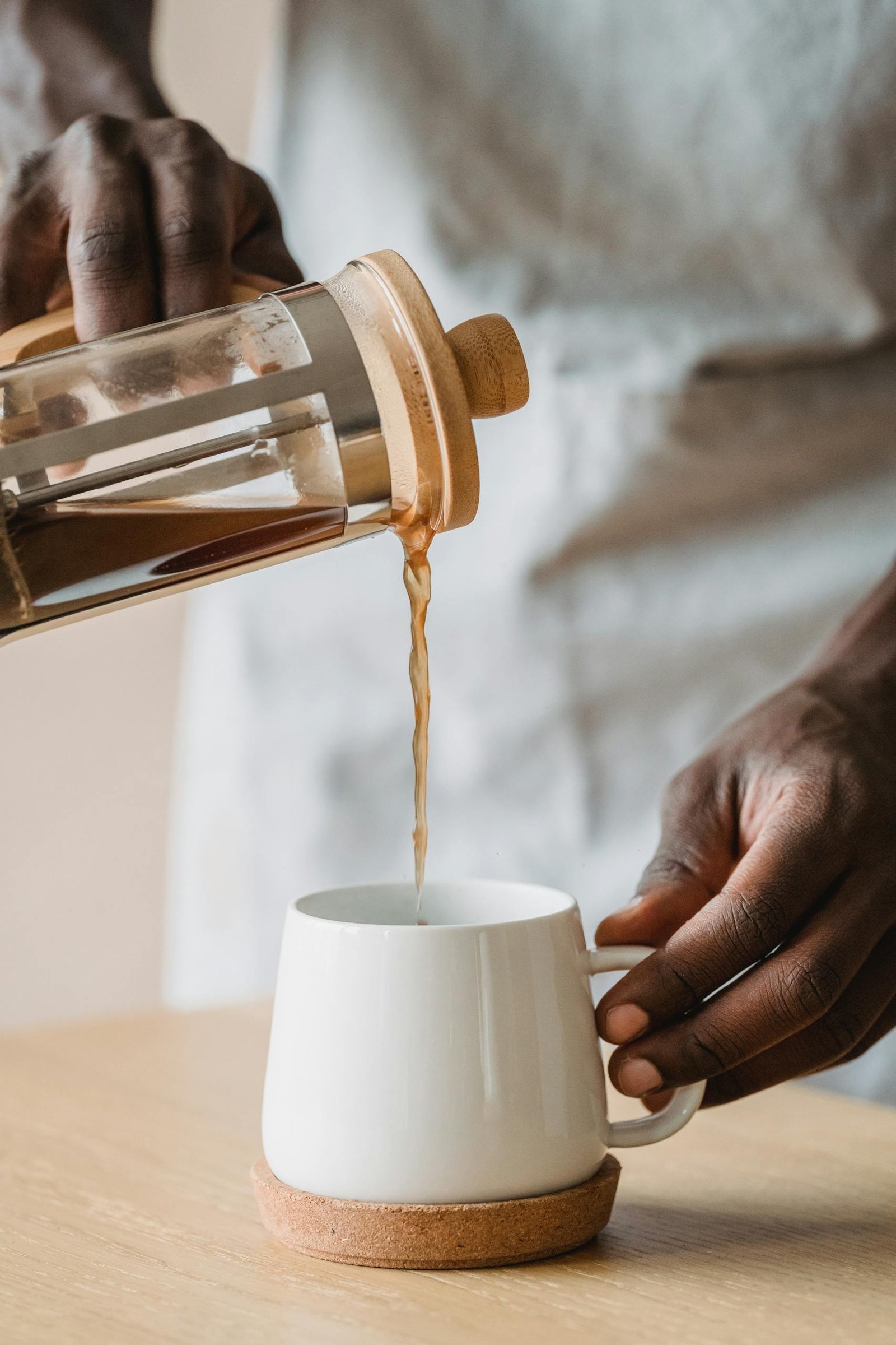 Man Pouring Coffee From a French Press Pot into the Cup