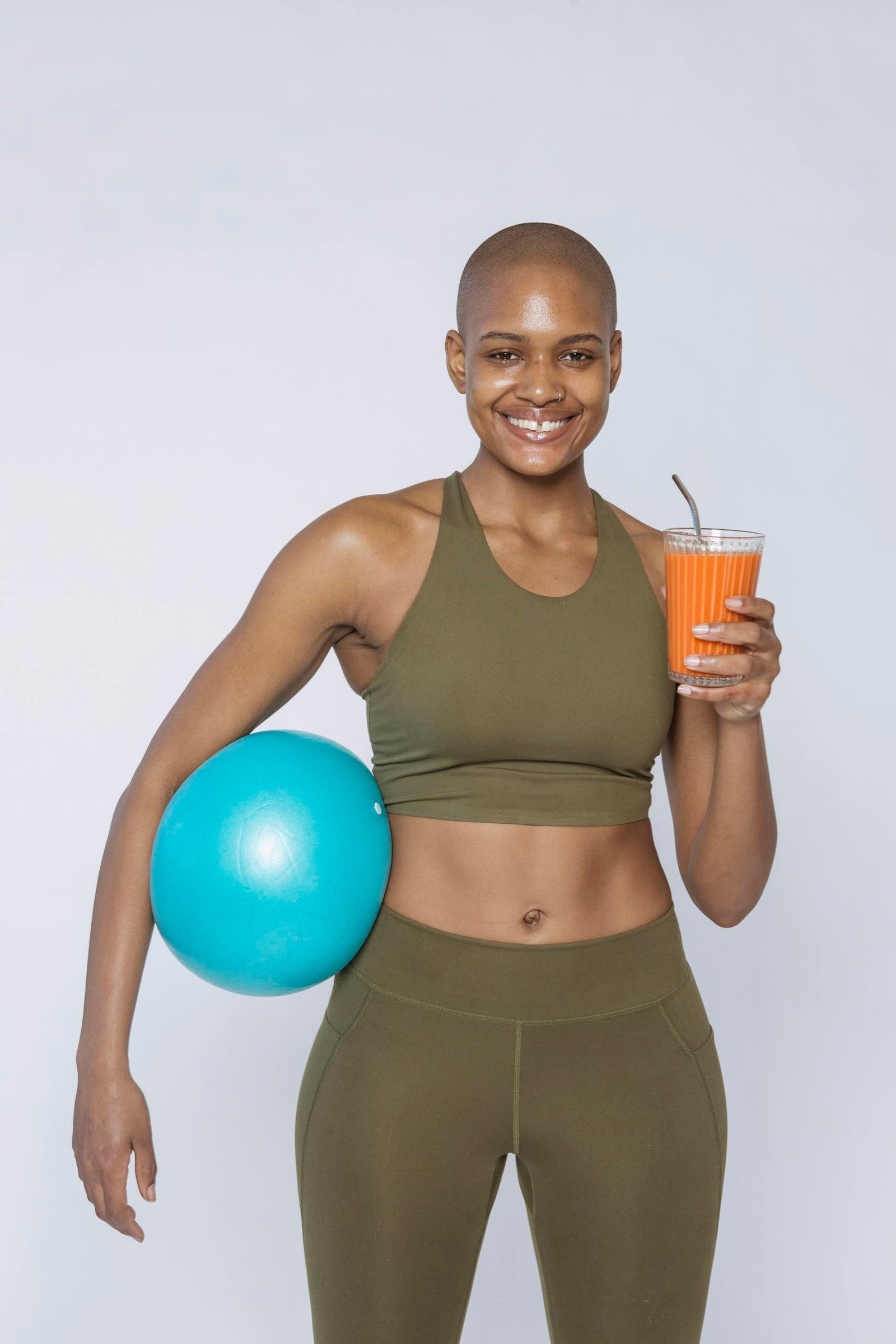 Smiling black sportswoman with smoothie and ball