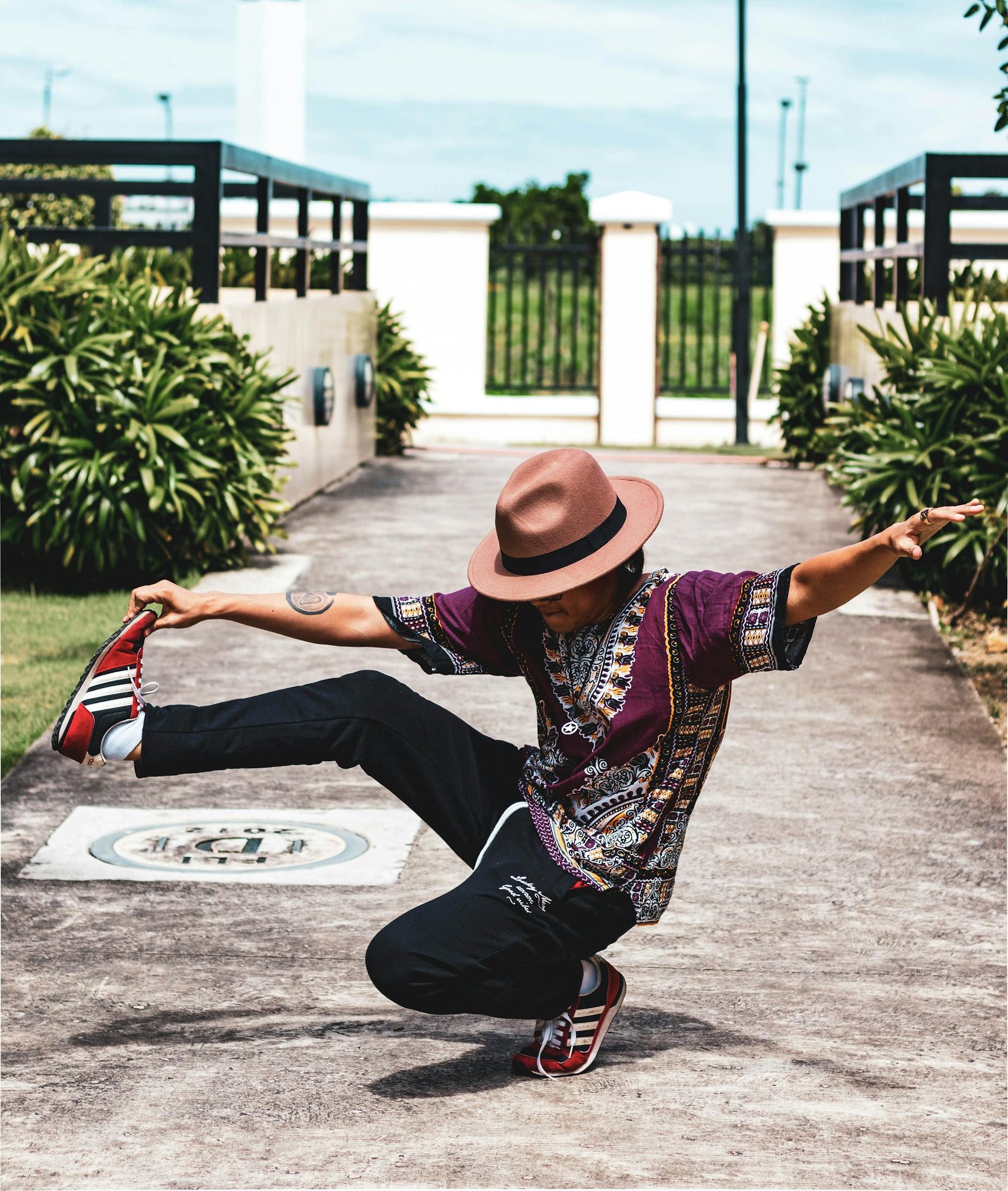 Unrecognizable ethnic dancer showing original trick on pavement near bushes